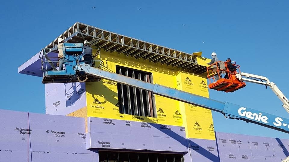 Crews on lifts installing sheathing around an exterior canopy