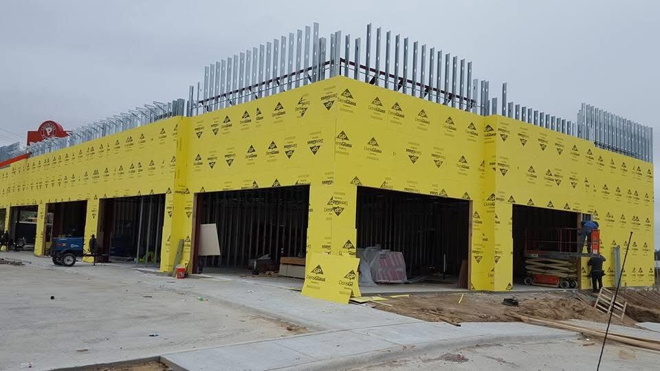 Commercial building with yellow exterior sheathing and storefront openings
